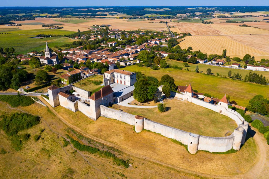 Drone view of medieval chateau and church in French village of Villebois-Lavalette on sunny summer day