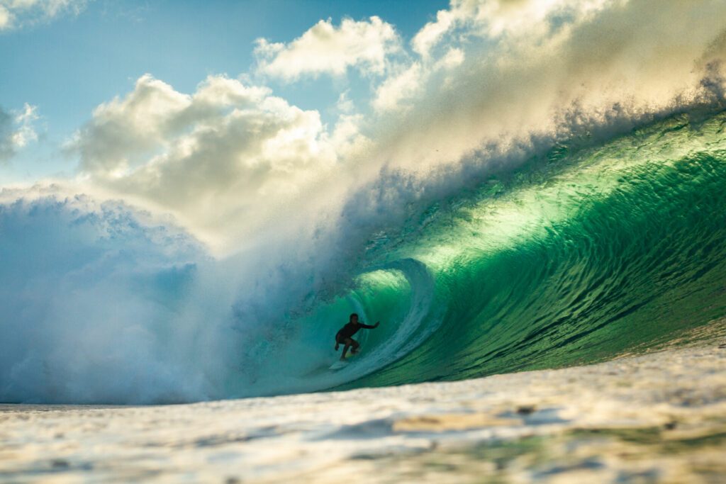 surfer riding a big barrelling wave at pipeline Hawaii