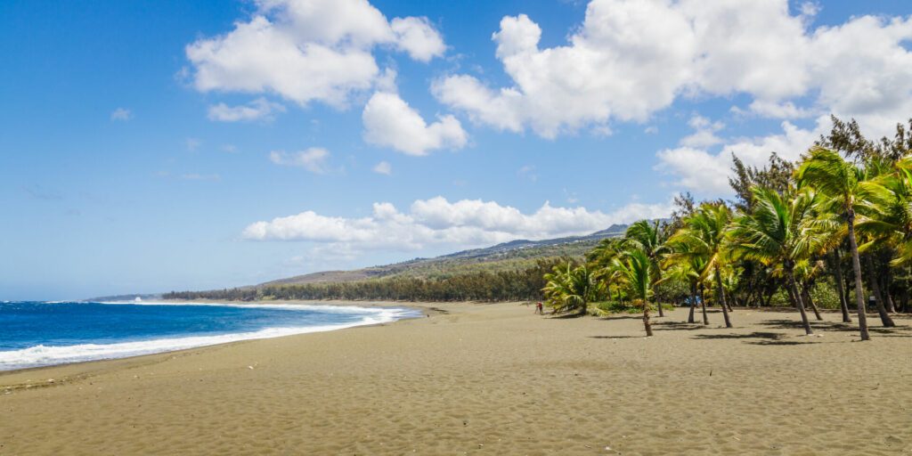 Etang-Sale beach on Reunion Island with its characteristic black sand and the waves of the Indian Ocean